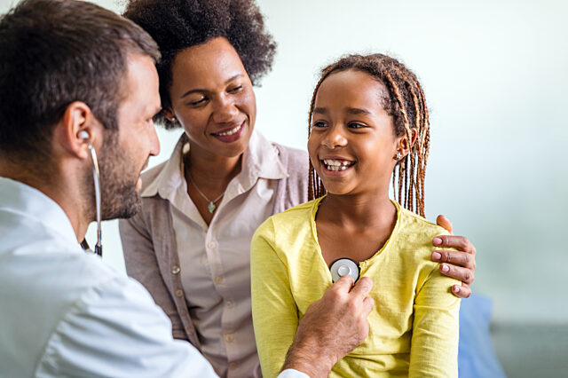 Healthcare medical exam people children and medicine concept. Close up of happy girl and doctor with stethoscope listening to heartbeat